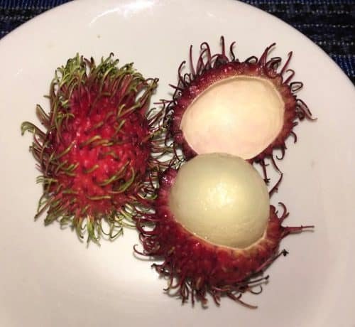 Rambutan: one with the skin and one cut open to reveal the fruit